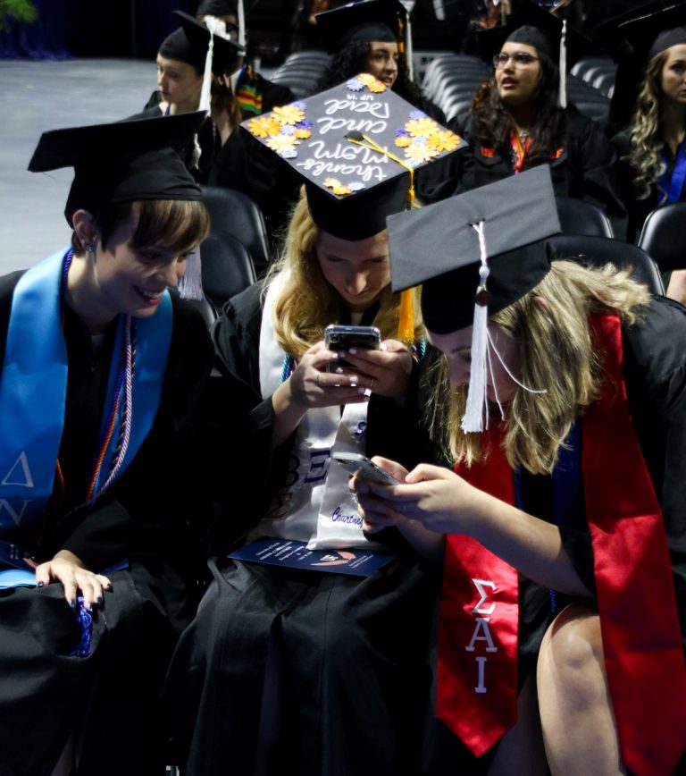 Graduating students playing on their phone