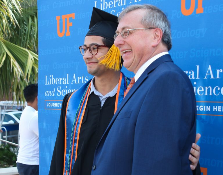 President Fuchs takes picture with graduating student