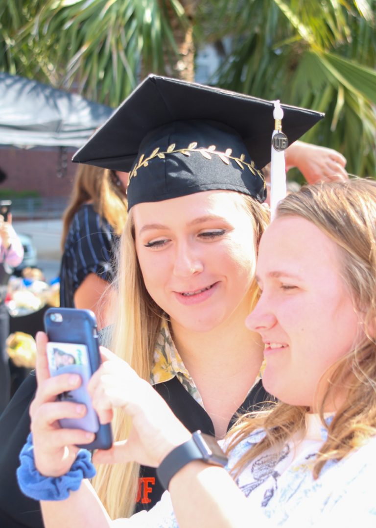 Graduating students looks at cellphone