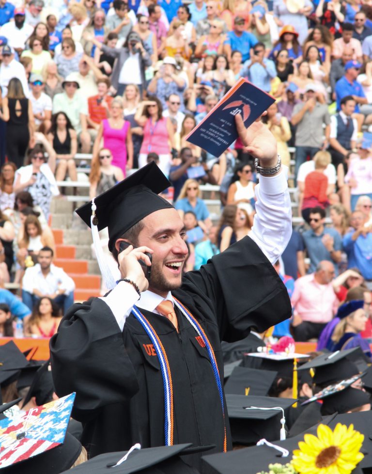 Graduating student on the phone waving at someone