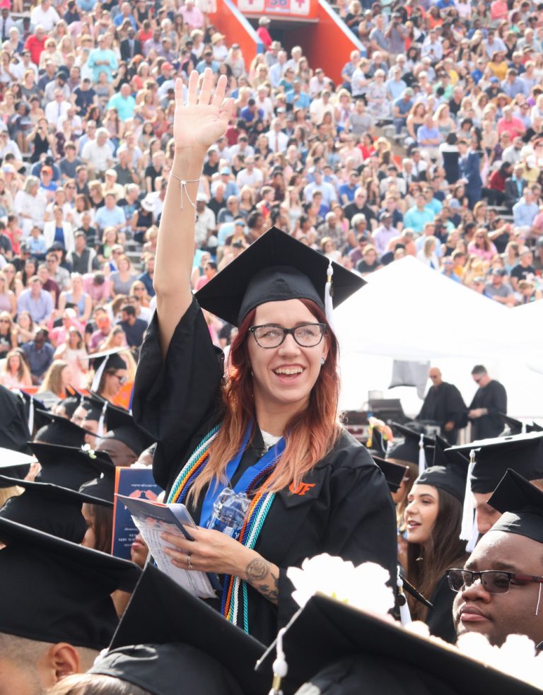 Graduating student waving at the crowd