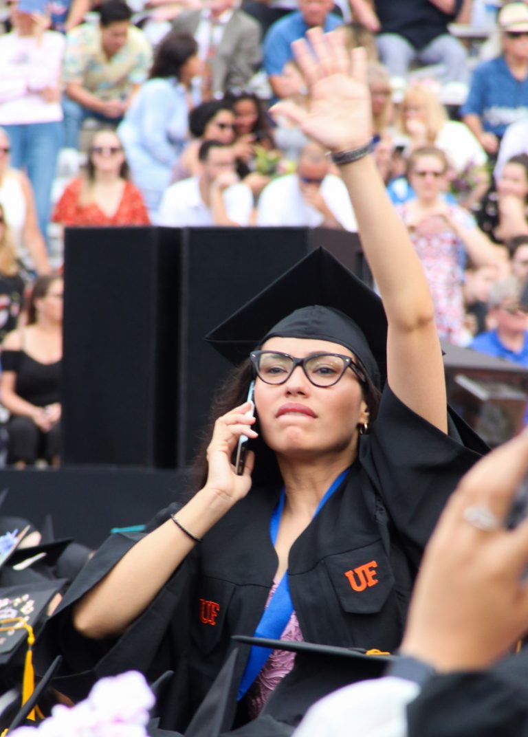 Graduating student on phone waving at someone