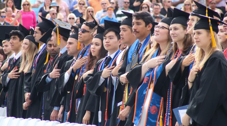 Graduating students with their hands over their hearts